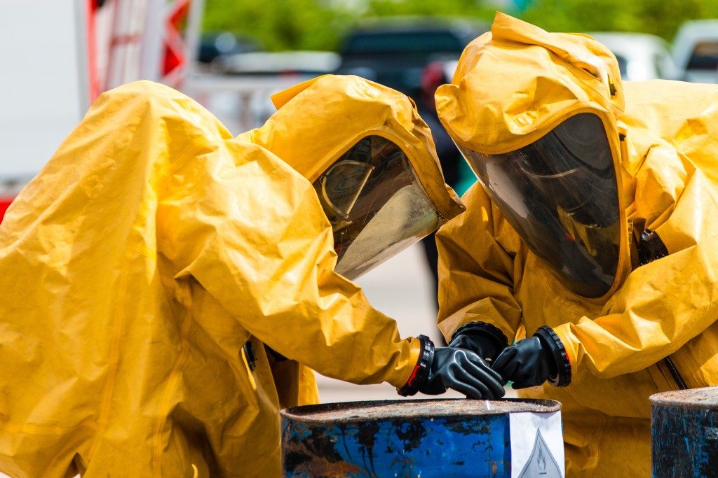 people wearing protective suits handling hazardous wastes