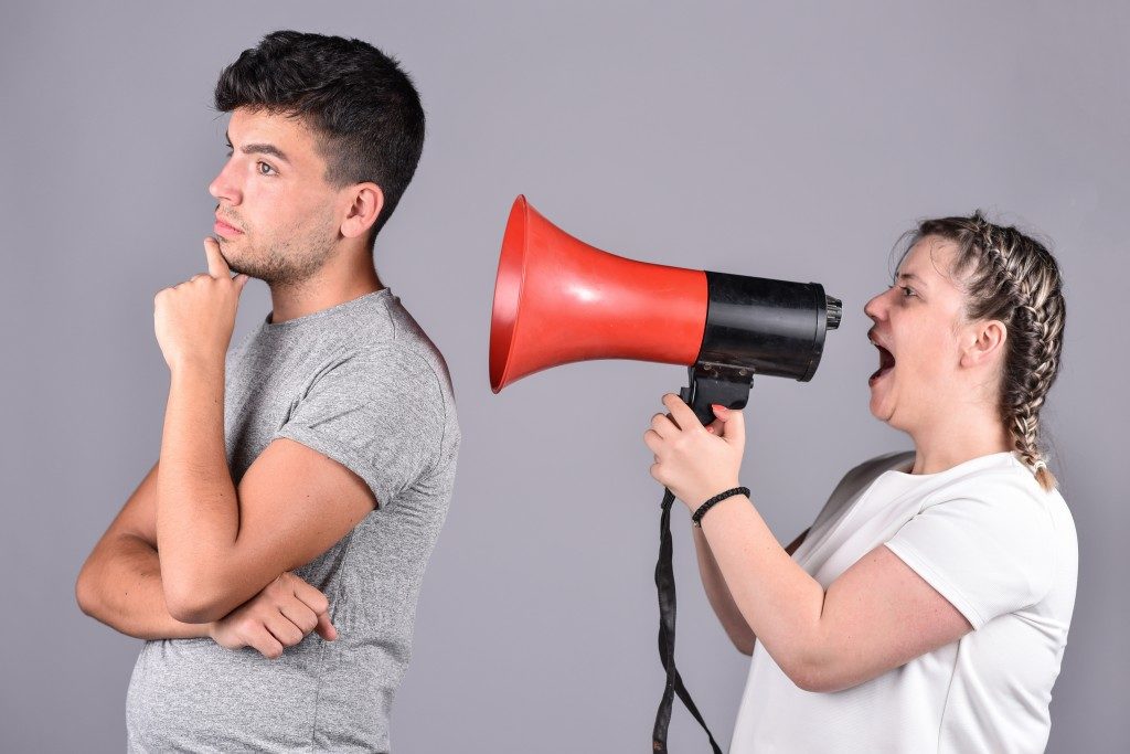 woman shouting on a megaphone infront of man
