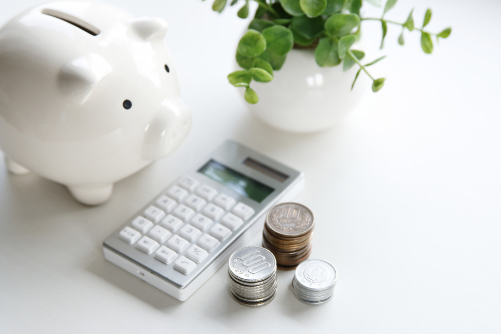 Calculator, stack of coins, and a piggy bank