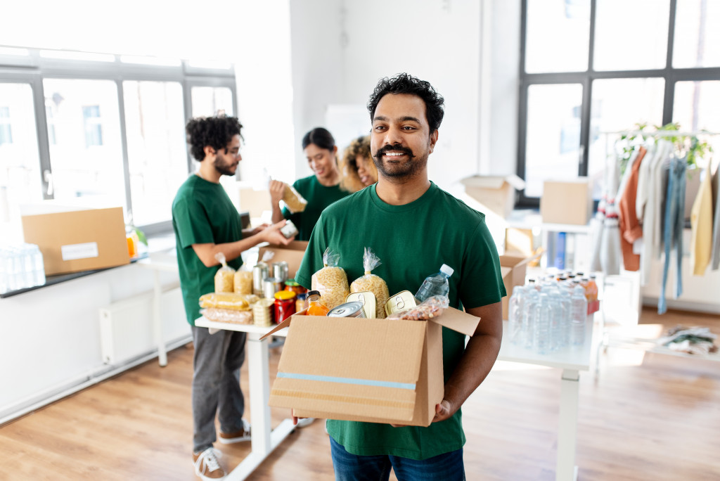 happy male volunteer with donation box filled with food