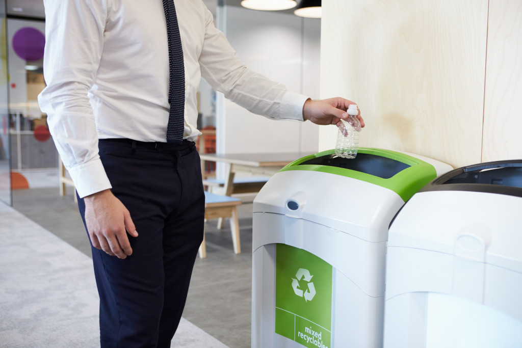 a man throwing a water bottle on a recycling bin