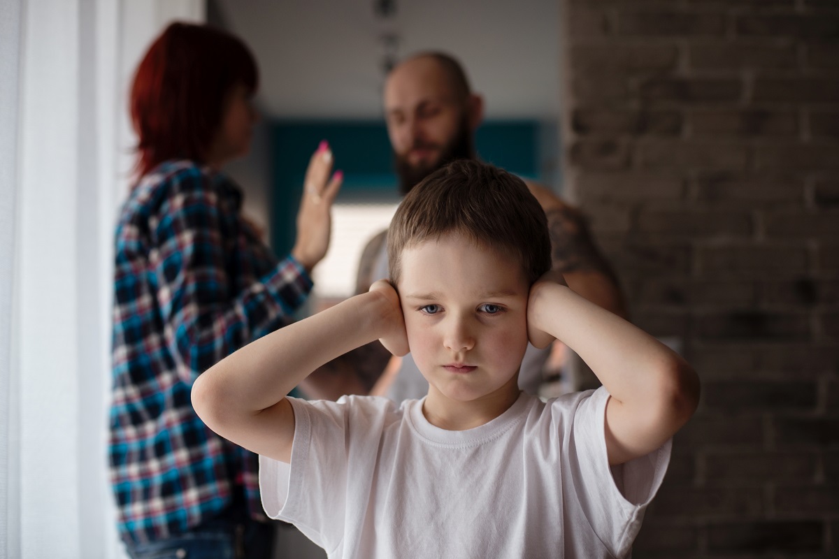 boy covering ear as couple fight